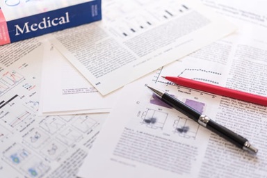 「Medical」と書かれた書籍と医療関連の書類が並ぶ写真。医療・臨床のデータ解析のイメージ